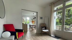 Ein modernes Wohnzimmer mit Essbereich, großen Fenstern und Blick ins Grüne.