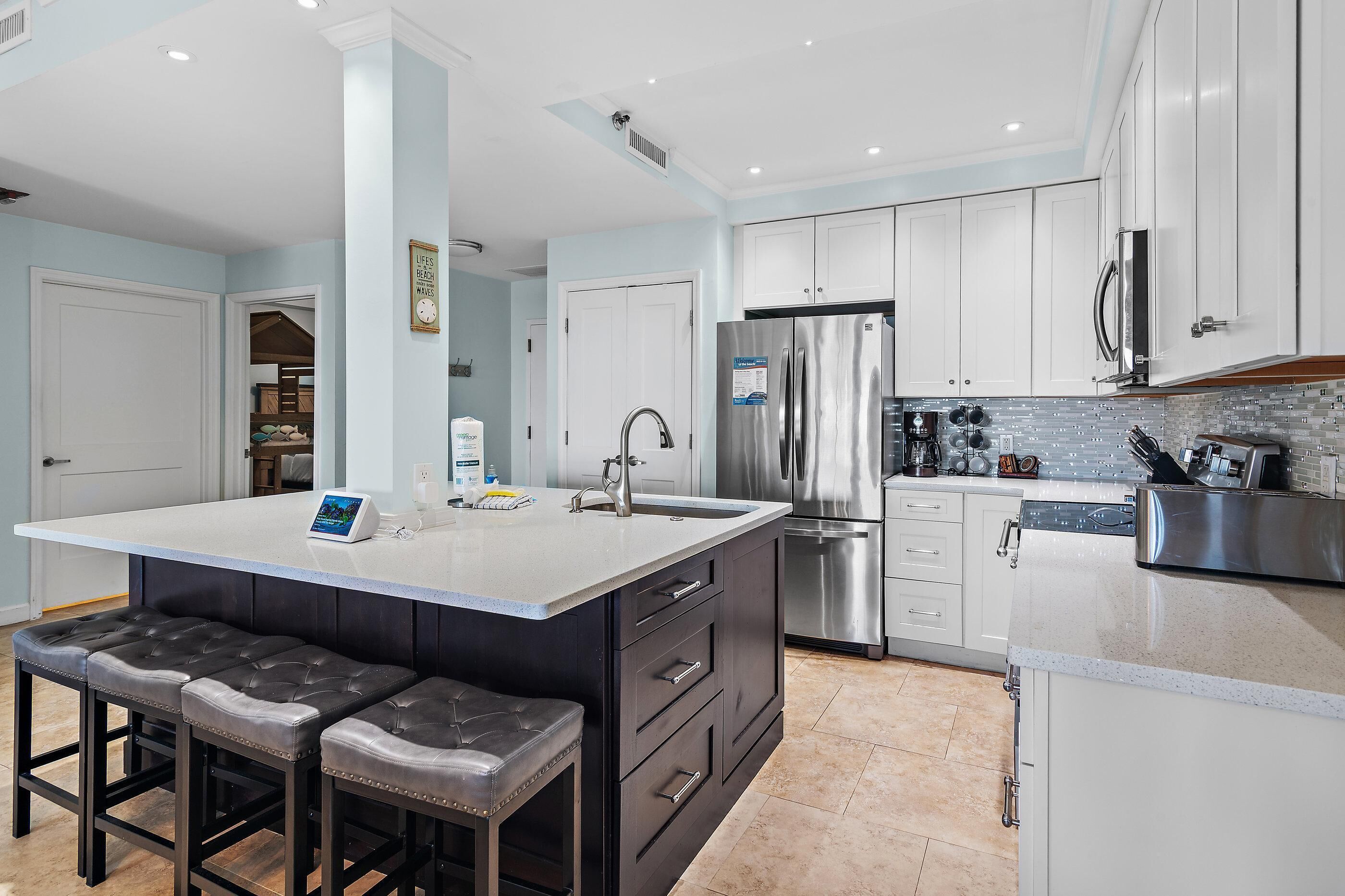 A modern kitchen with a central island, stainless steel appliances, and a seating area with stools.