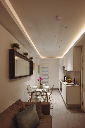 A modern kitchen with a dining area, a sofa, and a mirror on the wall. - Stylish 2BR Apartment Steps from the Beach (Sliema)