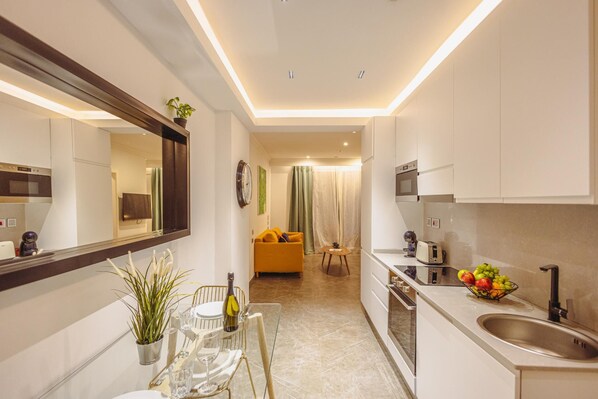 A modern kitchen with a dining area, a built-in oven, and a microwave. - Stylish 1BR Apartment Steps from the Beach (Sliema)