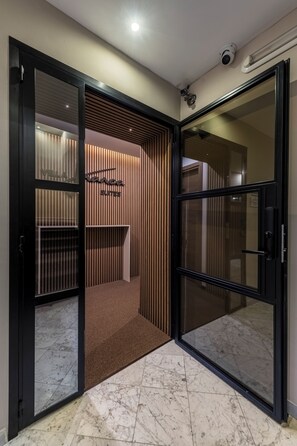 A hotel entrance with a modern design, including a sliding door, a reception area with a sign, and a security camera. - VillaFranca Suites Guest House (Roma)