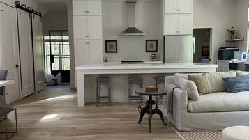 A modern kitchen with white cabinetry, a central island, and a dining area with a round table.