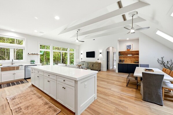 A modern kitchen with a large island, white cabinetry, and a dining area with a table and chairs.