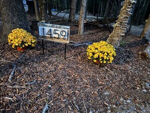A numbered signpost in a wooded area with mulch and yellow flowers.