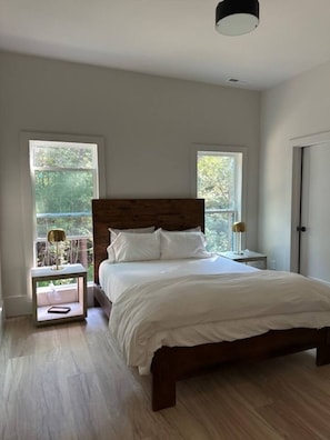 Quarto com cama de madeira, duas mesas de cabeceira e uma janela.