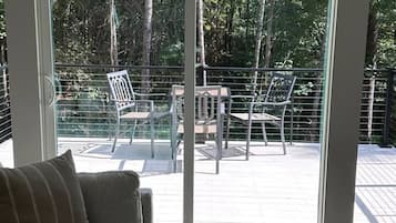 A room with a large sliding glass door leading to an outdoor deck with chairs and tables.