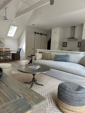 Um espaço de estar moderno estilo loft, com área de refeições, sofá, mesa de centro e cozinha.