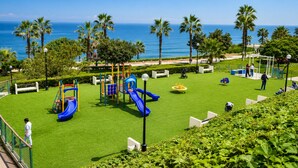 A playground with slides and climbing structures, surrounded by palm trees and a view of the ocean. - Spacious 3-Bedroom Apartment in Miraflores | Fast WiFi | Parking | Near Ocean View (Miraflores)