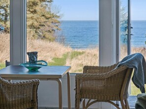 Ein Zimmer mit Tisch und Stühlen, Blick aufs Meer und einer Tür mit Schloss.