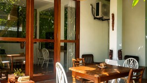 A dining area with a wooden table and chairs, a hanging wicker light fixture, and a view through glass doors to an outdoor space. - this is turtle paradise, Bentota Sri Lanka (Kosgoda)