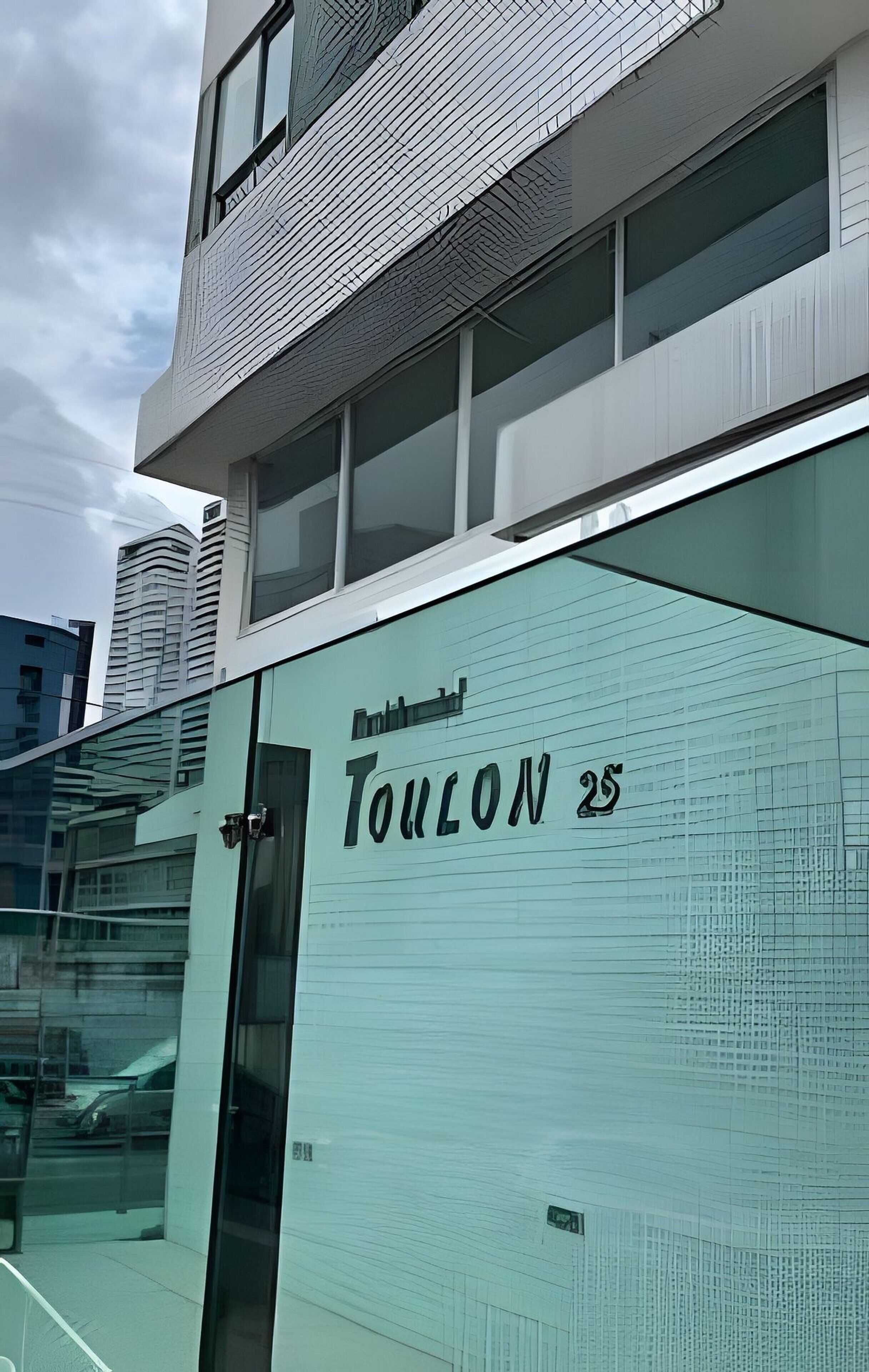 A modern building with a glass facade and the name 'TouLON 25' on the side.