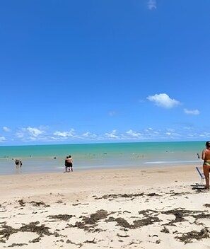 Une plage avec un ciel dégagé, une eau calme et peu de monde.