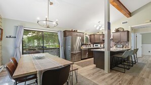 Une cuisine moderne dotée d’un grand îlot central, d’appareils électroménagers en acier inoxydable et d’un coin repas offrant une vue agréable.