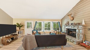 Ein Wohnzimmer mit Kamin, Fernseher und großem Fenster.