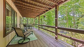 Eine Holzterrasse mit einer Pergola, einem Schaukelstuhl und einem Tisch mit Stühlen.