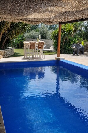 Ein Schwimmbecken mit Holzterrasse und Tisch mit Stühlen.