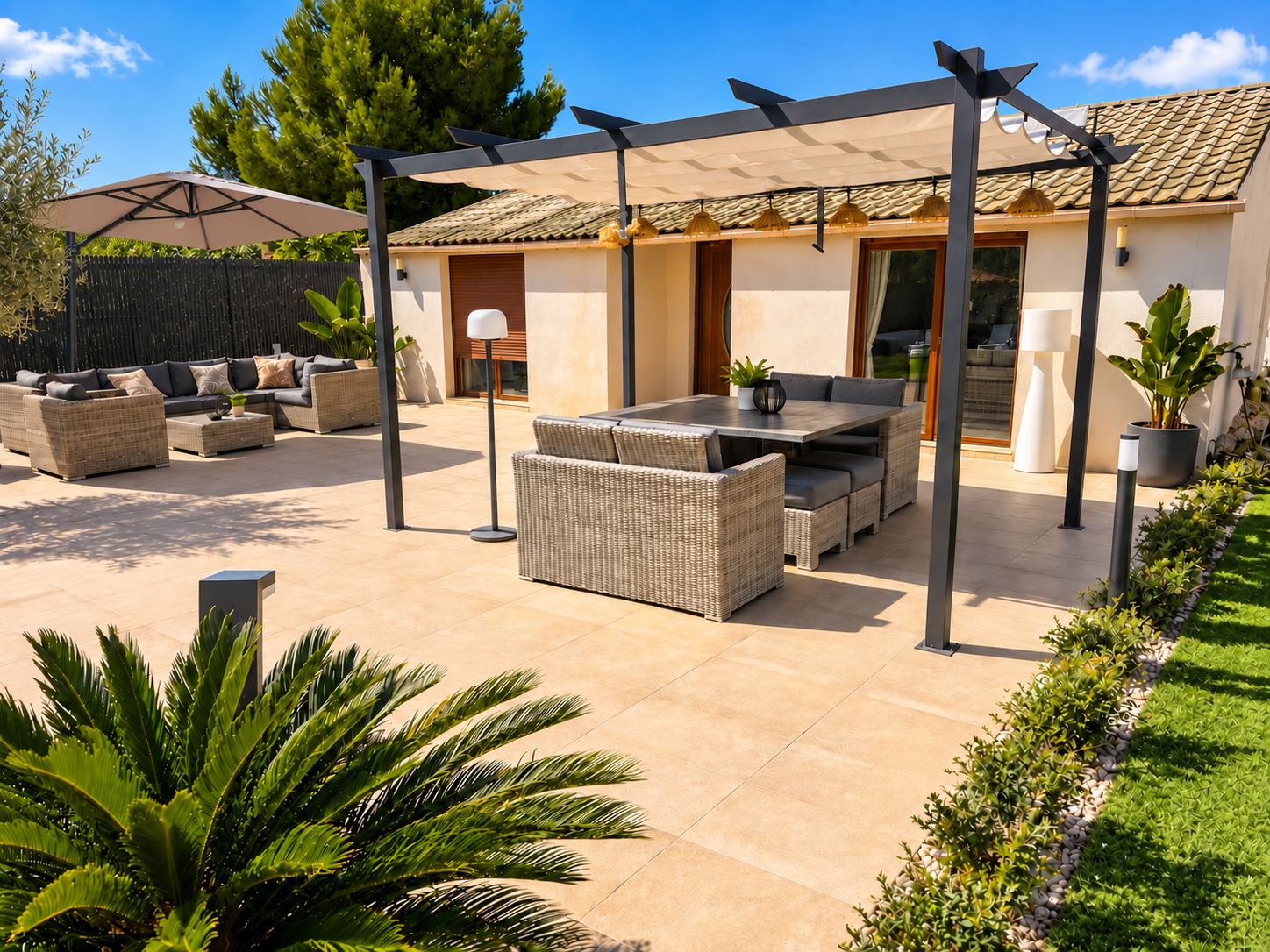 Un espace patio aménagé avec du mobilier d’extérieur, une pergola et une maison en arrière-plan.