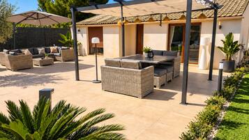 Un espace patio aménagé avec du mobilier d’extérieur, une pergola et une maison en arrière-plan.