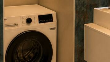 A compact, modern laundry room with a front-loading washing machine, a built-in sink, and a marble backsplash.