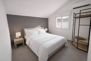 Ein Schlafzimmer mit einem Bett, Nachttischen, einem Fenster und einer eingebauten Ablage.