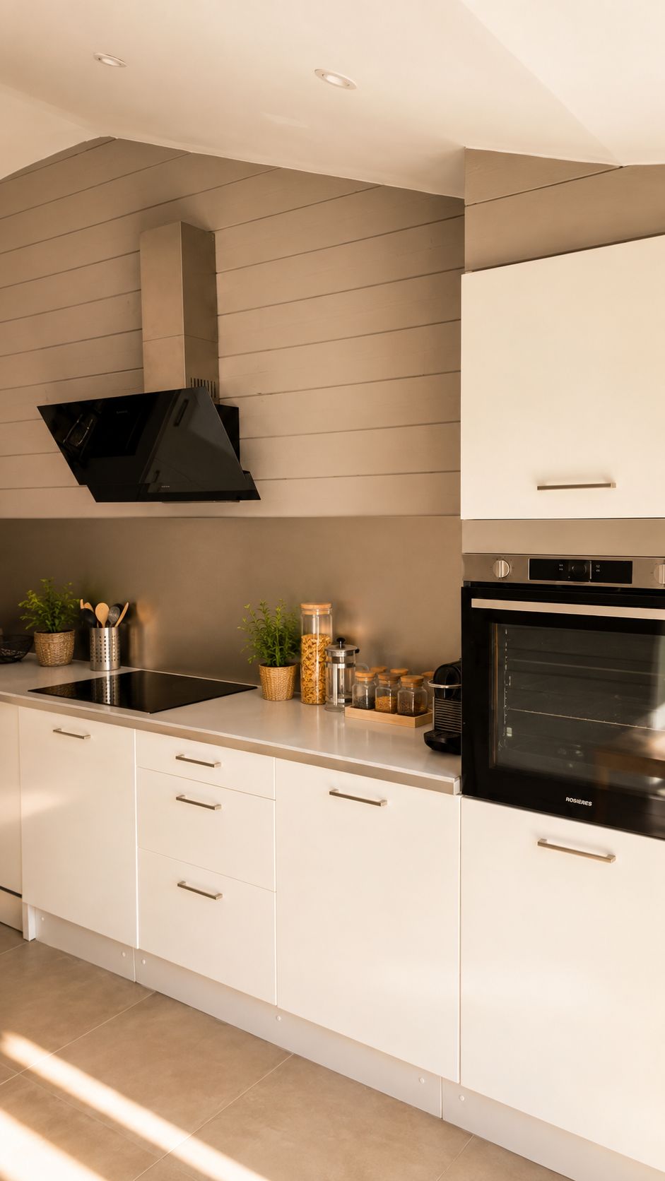Eine moderne Küche mit eingebautem Backofen, Dunstabzugshaube und Arbeitsplatte aus Edelstahl.
