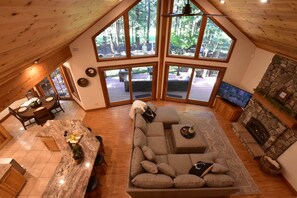 A spacious loft-style room with a large window, a stone fireplace, and a cozy seating area.