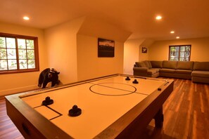 A room with a foosball table, a sofa, and a window.