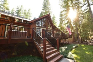 A wooden cabin with a staircase leading to a deck, surrounded by trees.
