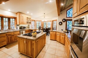 Una cocina amplia con armarios de madera, una isla central y un ventanal que proporciona luz natural.