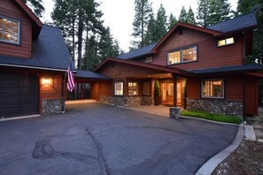 A two-story house with a stone foundation, a garage, and a driveway.