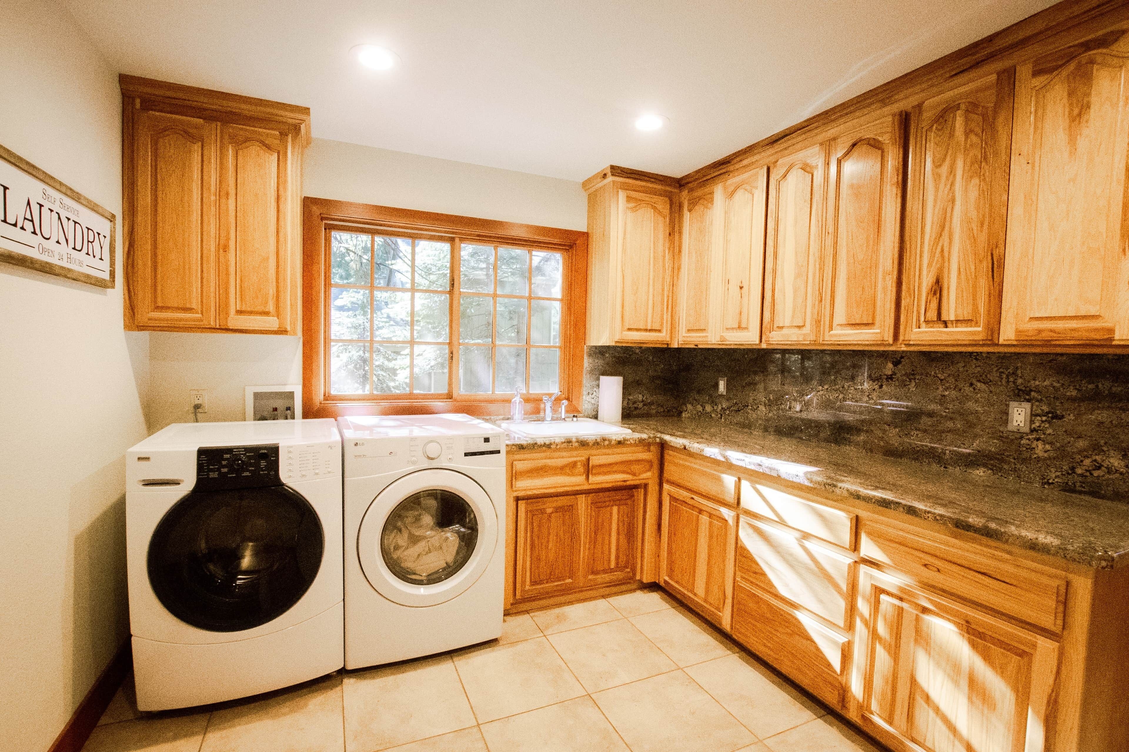 A laundry room with wooden cabinets, a washing machine, and a dryer.