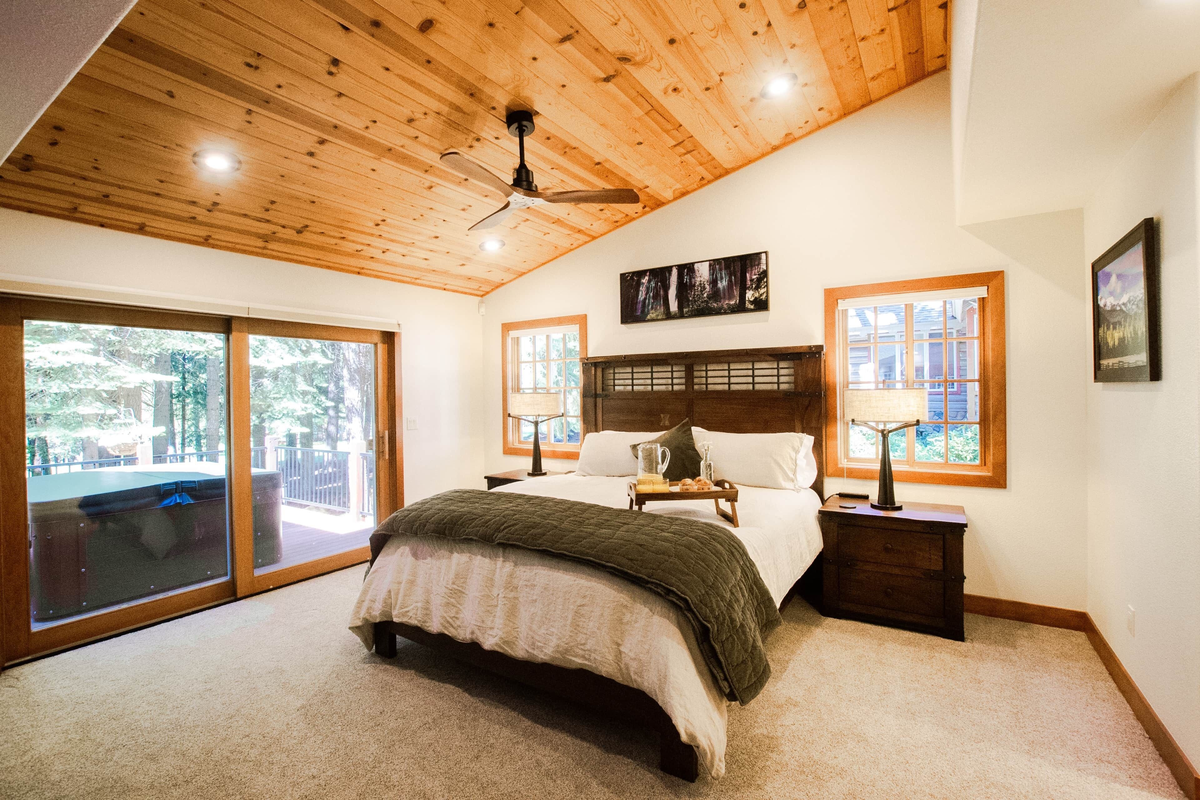 A bedroom with a bed, a nightstand, a ceiling fan, and a large window.