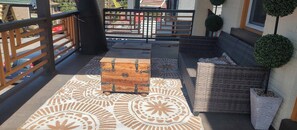 A balcony with a patterned floor, a wooden chest, wicker furniture, and potted plants. - Perfect 3-bedroom house in the heart of Mt. Washingston (Pittsburgh)