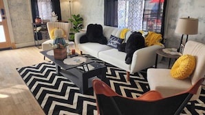A living room with a sofa, armchair, coffee table, and a lamp. - Perfect 3-bedroom house in the heart of Mt. Washingston (Pittsburgh)