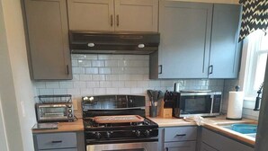 A modern kitchen with grey cabinets, a stainless steel stove, a microwave, and a toaster. - Perfect 3-bedroom house in the heart of Mt. Washingston (Pittsburgh)