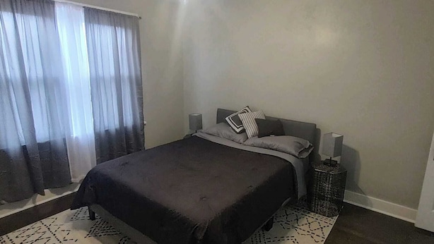 A bedroom with a bed, curtains, a bedside table, and a door. - Perfect 3-bedroom house in the heart of Mt. Washingston (Pittsburgh)