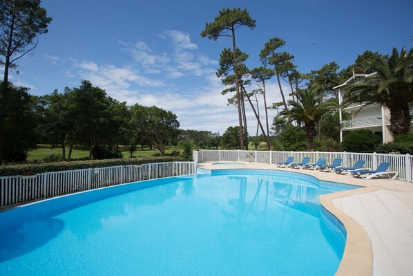 Une piscine avec des chaises longues et une clôture blanche.