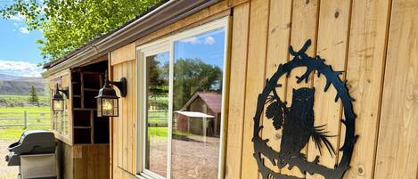 A wooden building with a 'WELCOME' sign, a bench, and a barbecue grill outside.