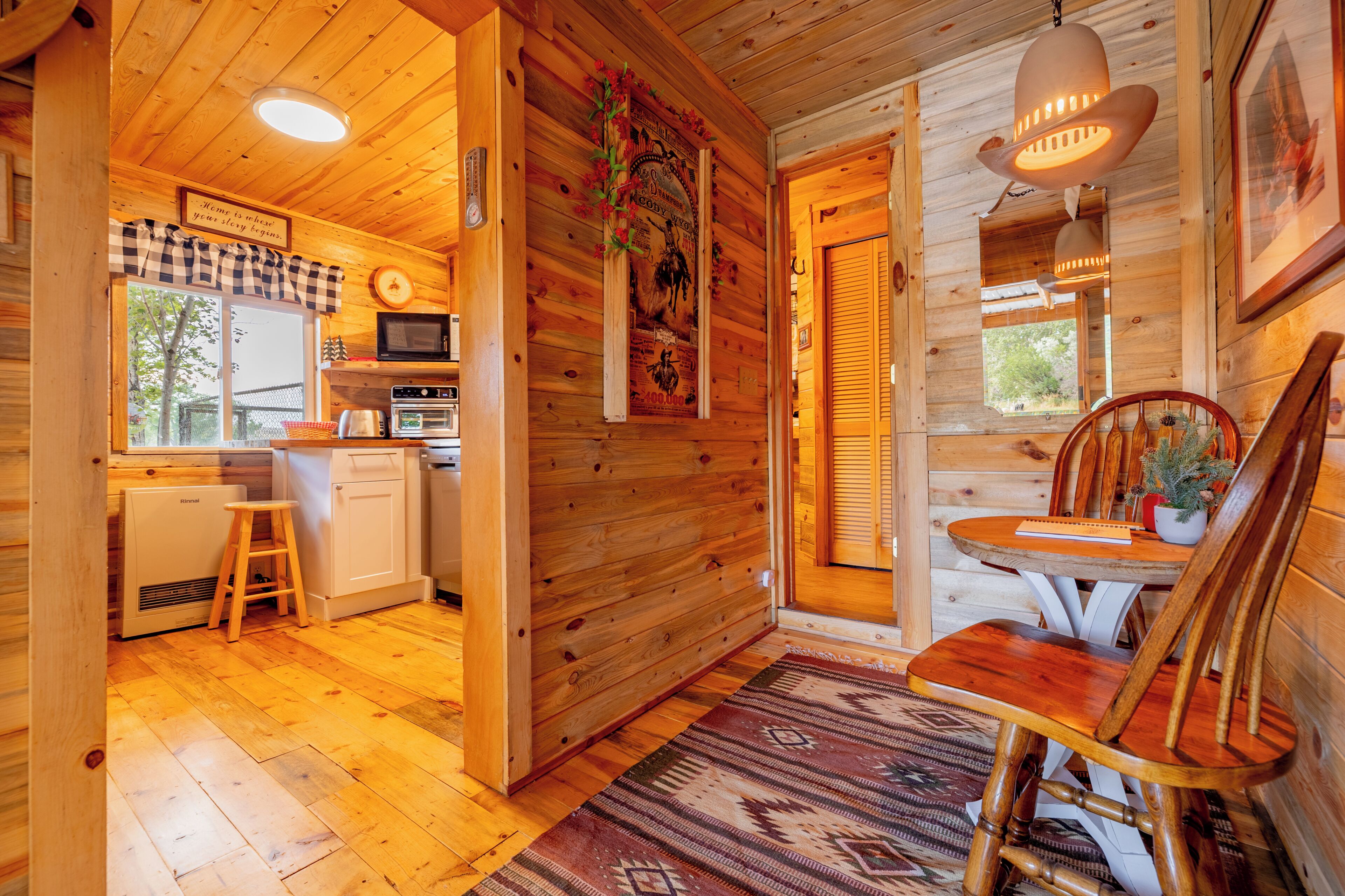 L’intérieur d’un chalet en bois comprend une cuisine, un coin repas et une porte visible qui donne sur l’extérieur.