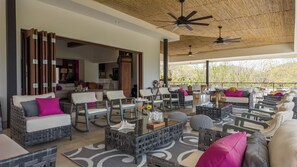 A spacious outdoor seating area with wicker furniture, a glass coffee table, and a ceiling fan. - Luxury Villa: Private Pool + Panoramic Ocean Views (San Juan del Sur)