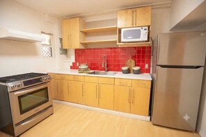 A kitchen with wooden cabinets, a stainless steel refrigerator, a microwave, a stove, and a red-tiled backsplash. - Airport Cozy 2 Bedroom Suite & Separate Entrances & Full kicthen (Richmond)
