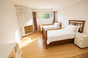 Ein Schlafzimmer mit Steinwand, einem Bett, einem Nachttisch und einem Fenster mit Vorhängen.