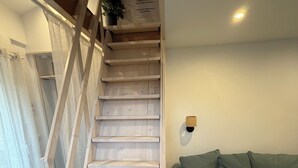 A staircase with wooden steps and a handrail, leading to an upper floor. - Quiet studio apartment (Aspremont)
