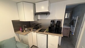 A compact kitchen with a sink, dishwasher, microwave, and coffee maker. - Quiet studio apartment (Aspremont)