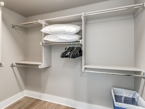 Ein begehbarer Kleiderschrank mit offenen Regalen, Kleiderstangen und einem Stauraumbehälter.