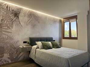 A bedroom with a bed, nightstand, and a window with a view. - Flower Beach Helgueras 2 - 6092 (Noja)