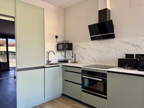 A modern kitchen with a built-in microwave, oven, and sink, and a large window providing natural light. - Flower Beach Helgueras 2 - 6092 (Noja)