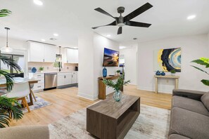 Ein modernes Wohnzimmer mit Essbereich, einer Küche und einem Deckenventilator.
