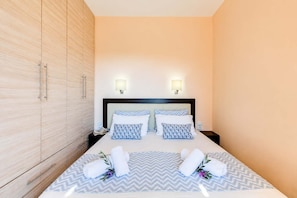Ein Hotelzimmer mit Bett, Nachttischen, einem Kleiderschrank und Wandleuchten.