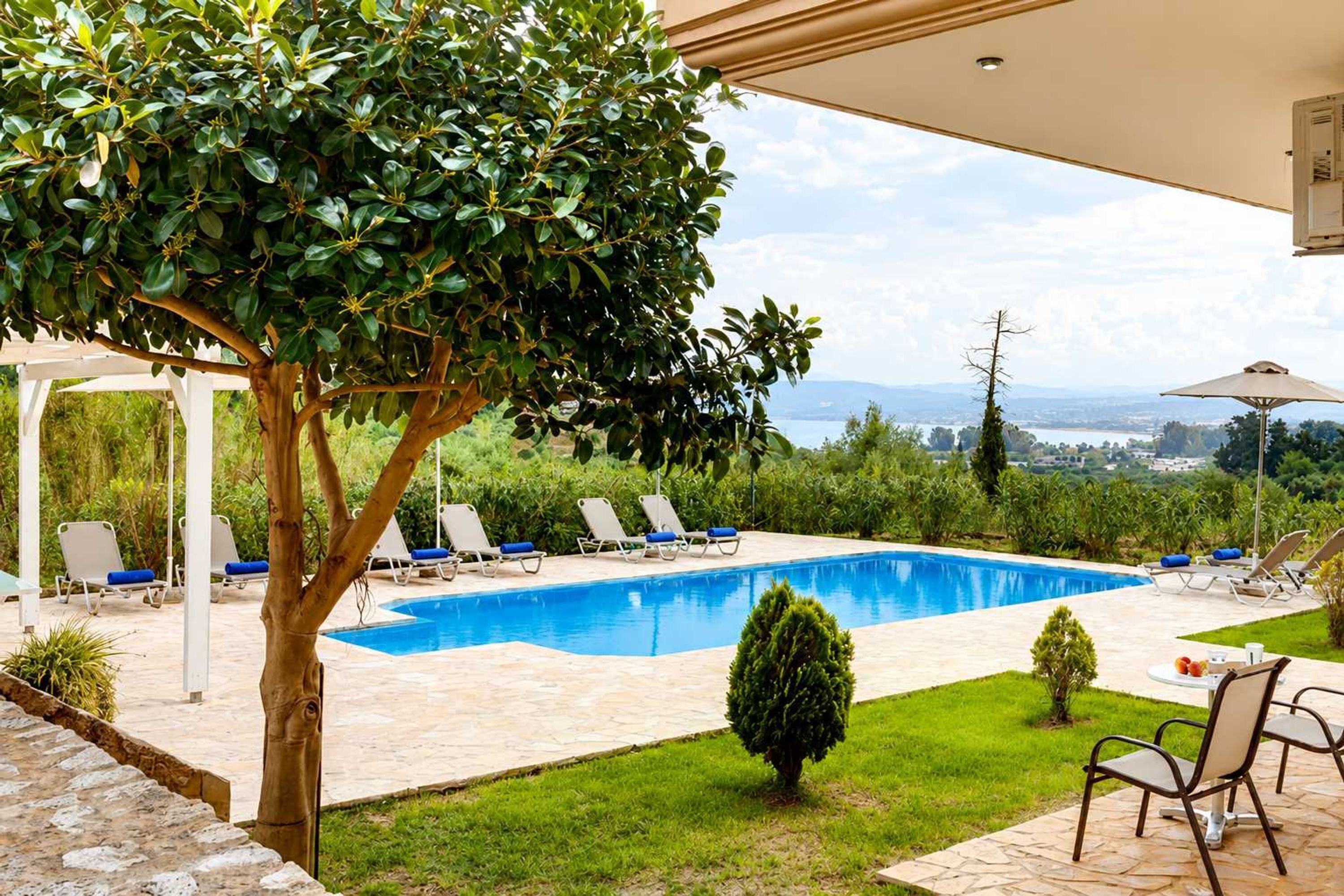 A swimming pool with lounge chairs, a small table, and a view of the landscape.